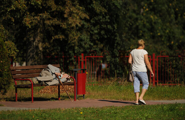 A stylish elderly man in a gray suit, gray cap, gray shoes and with a cane lies on a bench in the street. 