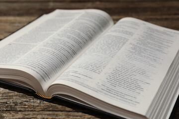 Obraz premium Open Holy Bible in English language on wooden table, closeup