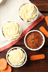 Fototapeta premium Delicious carrot muffins and fresh vegetables on wooden table, flat lay