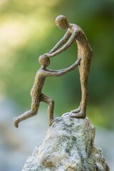 Fototapeta premium Two figures helping each other atop a rock.