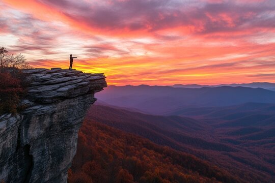 Hiker contemplating scenic sunset over appalachian mountains from mcafee knob