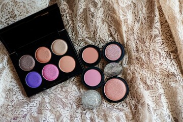 A grunge-inspired makeup setup featuring bold eyeshadows, glittery blushes, and shimmering highlighters, arranged beside a textured lace gown.