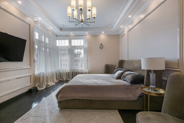 The interior of a modern bedroom with furniture. Windows with beautiful tulle, light carpet.