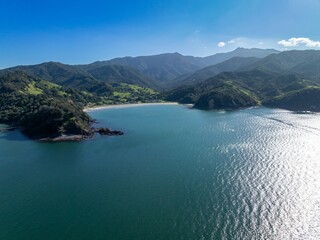Aerial view of a tranquil bay, nestled between lush green hills. Coastal town with homes along the...