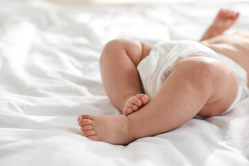 Cute little baby in diaper on bed, closeup