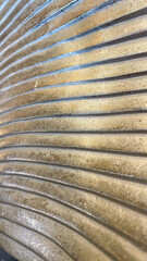 Close-up of a textured golden sculpture with linear patterns, captured in Plovdiv, Bulgaria. Ideal for concepts of luxury, modern design, and artistic decoration in commercial or personal spaces.