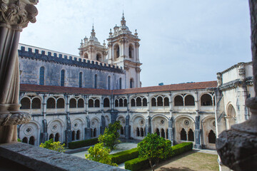 Obraz premium picturesque view through a stone archway, showcasing the architectural grandeur of a historic monastery with its ornate facade, intricate details, and a lush green courtyard