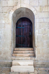 Obraz premium weathered wooden door framed by a stone archway, leading into a historic building and creating a sense of mystery and intrigue.