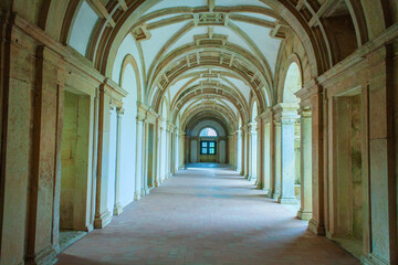 arched corridor with a tiled floor and sunlight streaming through the windows, creating a sense of mystery and intrigue within the historic building.