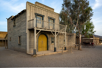 Rustic Western Building with Yellow Door and Balcony, Showcasing Weathered Charm and Historical Heritage in a Cinematic Frontier Setting