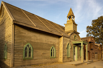 Rustic Wooden Church with Green Trim and Bell Tower: A Historical Gem Reflecting Quaint Charm and Traditional Craftsmanship in a Serene Countryside Setting