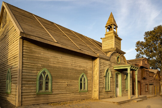 Rustic Wooden Church with Green Trim and Bell Tower: A Historical Gem Reflecting Quaint Charm and Traditional Craftsmanship in a Serene Countryside Setting