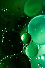 Green bubbles floating in liquid create an abstract visual in a dark setting