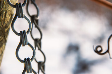 Closeup of vineyard trellis end posts chains hanging on a snowy branch in winter. Vineyard covered...