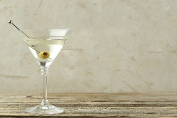 Martini cocktail with olive in glass on wooden table, space for text