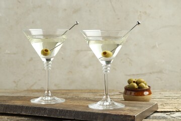 Martini cocktail with olives in glasses on wooden table