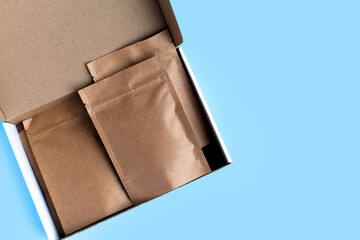 Kraft brown paper empty bags isolated mock up on light blue background. Eco friendly pack with zipper, roasted specialty coffee beans, tea, snack, alternative sample trendy concept. top view, flat lay