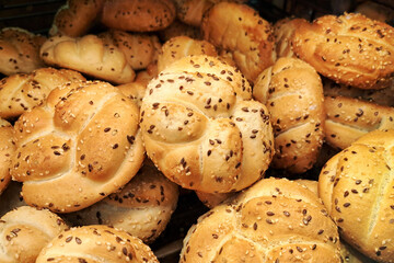 Fresh sesame Kaiser rolls on a bakery shelf. Golden brown buns topped with sesame seeds. Crisp and freshly baked rolls for breakfast or sandwiches. Bakery display of classic bread rolls.
