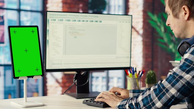 Software engineer at computer coding, creating software using isolated screen tablet. IT specialist in home office working with code editor, building applications using PC and mockup device, camera B