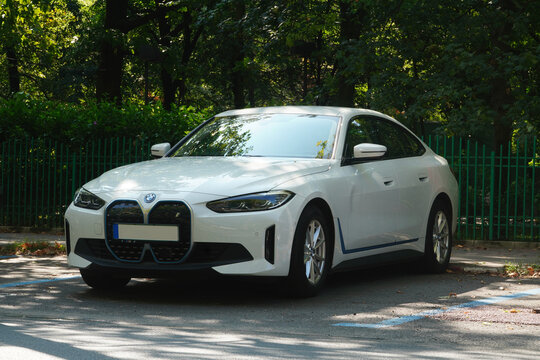 Bucharest, Romania - July 22, 2024: Front side view of BMW i4 edrive40 white electrical car parked on parking lot in front of park fence
