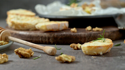 Rustic bread slices with rosemary and walnuts on a wooden board, accompanied by a honey dipper, creating a cozy and appetizing scene