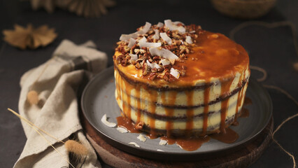 Layered cake drizzled with caramel sauce, topped with pecans and coconut flakes