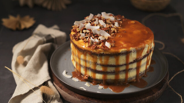 Layered cake drizzled with caramel sauce, topped with pecans and coconut flakes