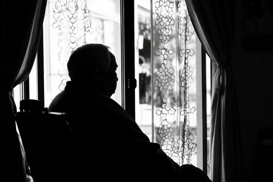 Lonely senior person in wheelchair gazes out the window during quiet afternoon