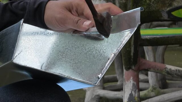 Close up of Technician solders gutters for customers.