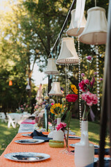 Elegant Outdoor Wedding Tablescape with Hanging Lampshades, Vibrant Flowers, and Artistic Table Settings for Memorable Event Decor Inspiration