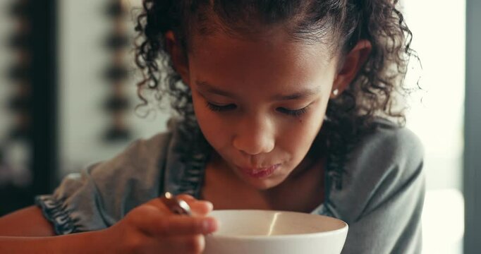 Child, eating and cereal for breakfast in kitchen with organic fibre, wheat nutrition and calcium growth. Girl, healthy food and diet meal in morning, milk benefits and childhood development at house