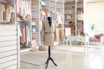 Interior of stylish boutique with clothes, mannequin and table