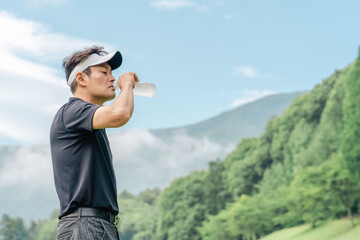 ゴルフラウンド中に水を飲むゴルファーの男性
