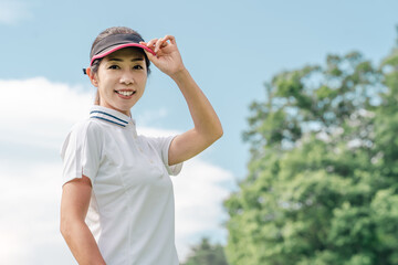 ゴルフ場でゴルフをするゴルファーの女性(笑顔)

