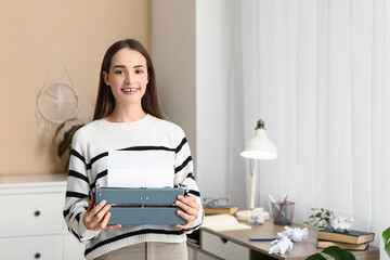 Beautiful happy female writer with typewriter at table home
