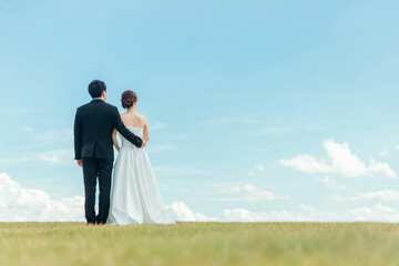 Fototapeta premium 空バックの新郎新婦の後ろ姿（ウェディング・結婚式・ブライダル・ロケーションフォト） 