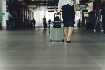 Fototapeta premium 駅でスーツケースを持った出張・旅行帰りの女性・ビジネスウーマンの足元 