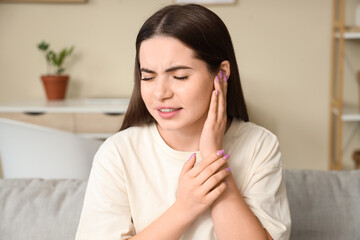 Young woman suffering from pain in ear at home