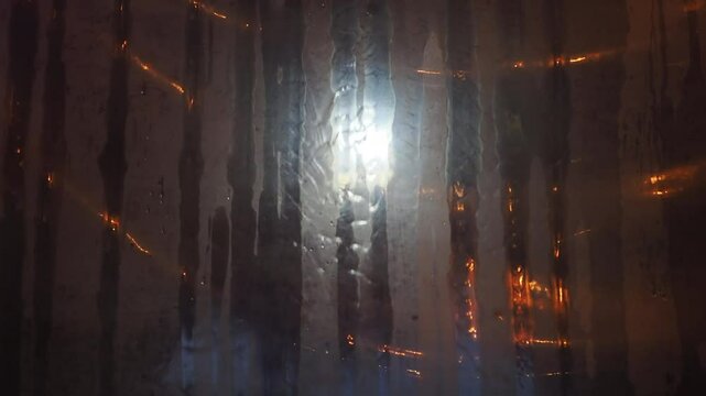Rain flows through the plastic awning at night.