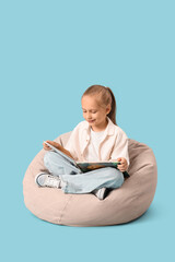 Funny little girl reading book on  blue background
