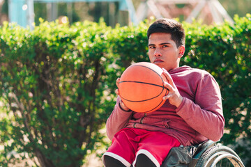 Young Latino man in wheelchair, pensive, holding and looking at ball, focused, preparing to play and train basketball