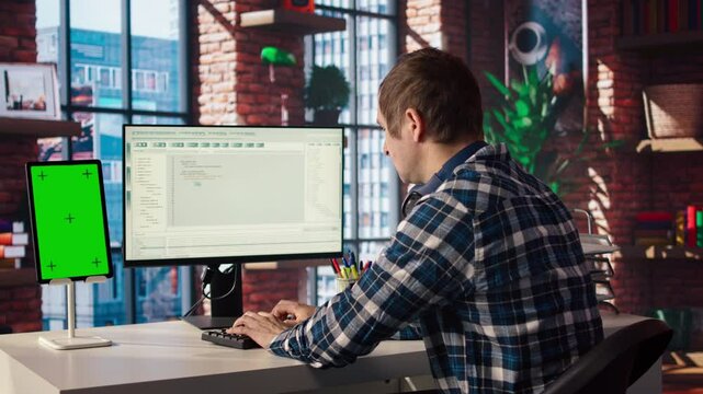 Software engineer at computer coding, creating software using isolated screen tablet. IT specialist in home office working with code editor, building applications using PC and mockup device, camera A