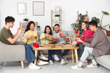 Group of friends with drinks eating pepperoni pizza at home party