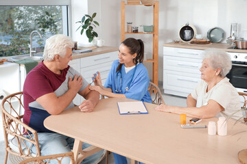 Fototapeta premium Diabetic senior couple with doctor using lancet pen in kitchen