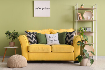 Yellow sofa, houseplants and pouf in interior of living room