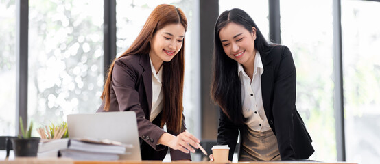 Two asian business women discuss data on document graph report. Meeting and Talking.advising each other in office,