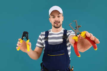 Male technician with wire strippers on blue background, closeup