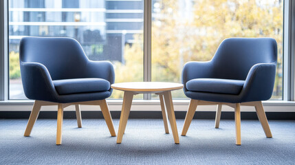Two blue armchairs and round wooden table by large window with city view