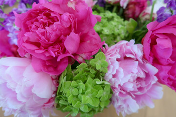 A vibrant floral arrangement featuring pink peonies, green hydrangeas, and soft pastel blooms in full detail, capturing the delicate textures and fresh beauty of nature.