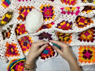 Crocheting granny square blanket process and woman's hands hobby handmade handiwork clews and hook cozy winter autumn fall photo